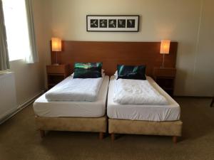 two twin beds in a hotel room with two lamps at Welcome Apartments in Ólafsvík