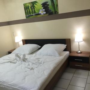 um quarto com uma cama com lençóis brancos e 2 candeeiros em Boulevard Apartment em Raunheim