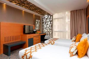 una camera d'albergo con due letti e una televisione di Grand Plaza Hotel - Gulf Riyadh a Riyad Altre 35 foto