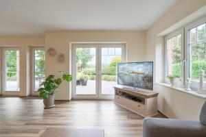a living room with a flat screen tv on a stand at Villa Kanalblick, Schiffsdeck in Oldenbüttel