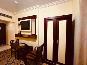 a hotel room with a television and a table and chairs at فندق الإجابة المكنونة in An Naqāʼ