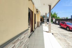 une voiture rouge garée dans une rue à côté d'un bâtiment dans l'établissement RedDoorz at NN Guest House Exit Tol Klodran Solo, à Solo