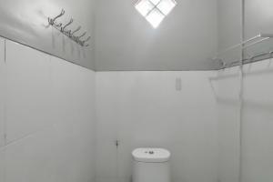 une salle de bain blanche avec toilettes et fenêtre dans l'établissement RedDoorz at NN Guest House Exit Tol Klodran Solo, à Solo