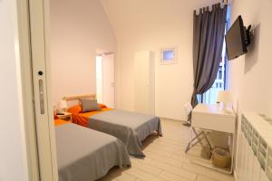 ナポリにあるNapoli a Festaのベッド2台とテレビが備わるホテルルームです。