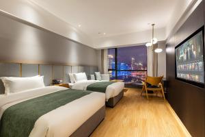 ein Hotelzimmer mit zwei Betten und einem Flachbildfernseher in der Unterkunft Chongqing From Hotel in Chongqing