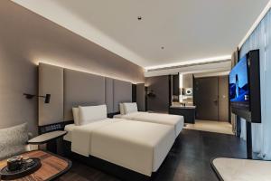 a hotel room with a white bed and a flat screen tv at Atour Hotel, Wending Road, Xujiahui Center, Shanghai in Shanghai