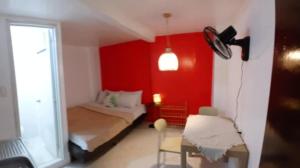 a bedroom with a red wall with a bed and a table at Silid Siargao in General Luna +2 photos