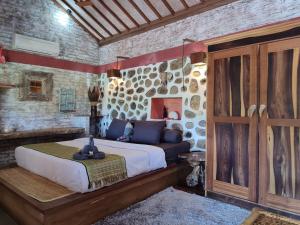 a bedroom with a large bed in a stone wall at Metis Eco Lodge in Kuta Lombok