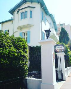 a white house with a sign in front of a fence at Hotel Alexandre III in Cannes