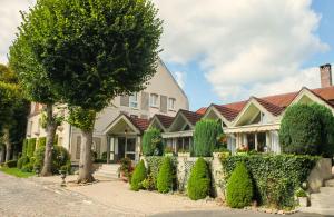 a row of houses with trees and bushes at Hôtel & Restaurant Le Relais d'Aumale in Orry-la-Ville