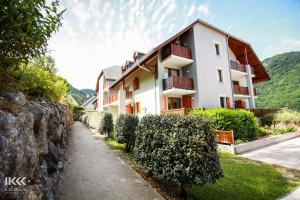 a building with a stone wall next to a sidewalk at Résidence Balcons de La Neste in Arreau