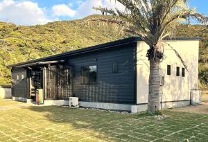 a house with a palm tree in front of it at ホシヤドリ hoshiyadori in Setouchi