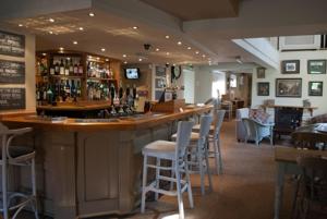 a bar in a restaurant with a bunch of stools at The Hare and Hounds in Fulbeck