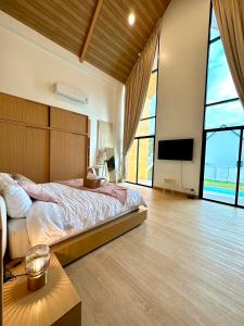 une chambre avec un grand lit et une télévision à écran plat dans l'établissement Montere Hus Pool Villa Khao Yai, à Wangkata