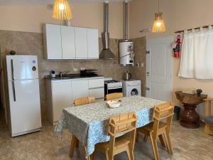 a kitchen with a table with chairs and a white refrigerator at Casa Ayacucho in Alta Gracia