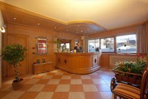 a man standing at a bar in a restaurant lobby at Hotel Angelica in Livigno