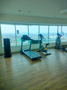 a gym with three exercise bikes in a room with windows at Apartement Grand Kamala Lagoon by Bekstay in Pulosirih