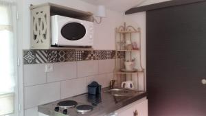 a kitchen with a microwave above a sink at Les Trois Roses in Abbeville