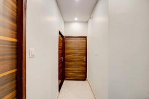 a hallway with a wooden door and white walls at Collection O IIT BHU Varanasi Formerly Singh Residency in Varanasi