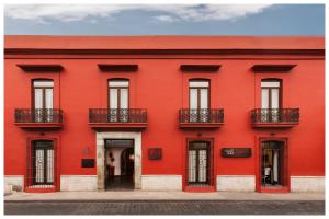 a red building with windows and balconies on a street at Hotel Abu in Oaxaca City