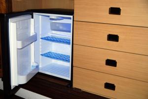 an empty refrigerator with its door open next to a dresser at Pensión Araba II in Vitoria-Gasteiz