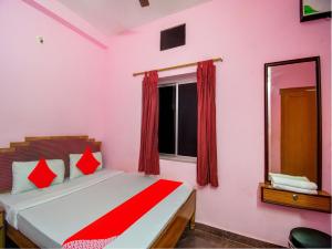 a bedroom with a bed with red curtains and a window at Hotel O Kolkata Palace in Puri