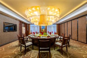 a dining room with a large table and a chandelier at Wuxi Winterless Hotel in Wuxi