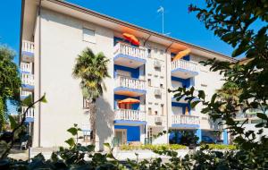 a white building with blue balconies and a palm tree at Ca'Costanza in Bibione