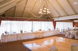 a banquet hall with white tables and chairs and a chandelier at Caravelle Resort in Myrtle Beach