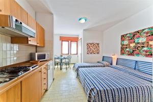 a room with two beds and a kitchen with a stove at Ca'Costanza in Bibione