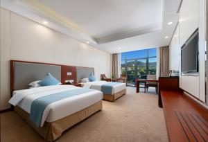 a hotel room with two beds and a flat screen tv at Wuxi Winterless Hotel in Wuxi