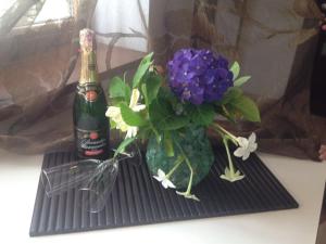 Una botella de champán y un jarrón de flores sobre una mesa. en Svetlana Guest House en Novy Afon