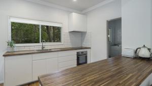 a kitchen with white cabinets and a sink and a window at Diamond Escape - Pearl in Umina
