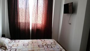 a bedroom with a bed with red curtains and a window at Apartament la mare Mamaia Nord in Mamaia Nord