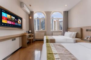 een hotelkamer met twee bedden en een flatscreen-tv bij Zhongmai Yunting Hotel in Harbin