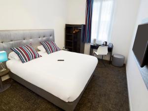 sypialnia z dużym białym łóżkiem i biurkiem w obiekcie Kyriad Marseille Blancarde - Timone w Marsylii