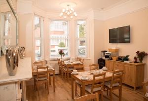 a dining room with tables and chairs and a television at The Guest House Broadstairs in Broadstairs