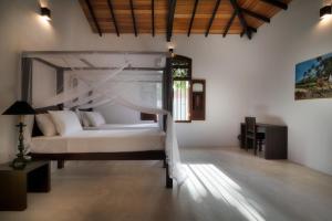 a bedroom with a white bed with a canopy at Villa by the River in Ambalangoda-Starflower Villa in Ambalangoda +13 photos