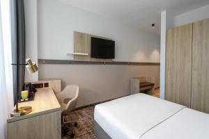 a bedroom with a bed and a tv on the wall at Wyndham Garden Munich Messe in Munich +66 photos