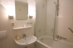 a white bathroom with a sink and a shower at City-Pension Magdeburg in Magdeburg