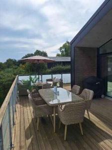 a table and chairs on a deck with an umbrella at Holiday Idyll With Nature And City Nearby in Skødstrup