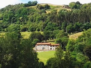 een huis op een heuvel in een groen veld bij Finca Artienza in Ramales de la Victoria