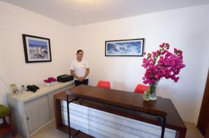 a man standing in a room with a vase of flowers at Casita de la Playa in Puerto Villamil