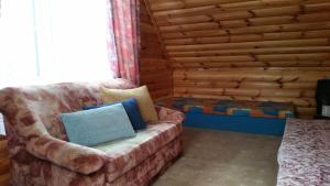 a living room with a couch and a log wall at Dom na Mazurach in Spychowo