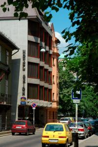 a yellow car driving down a city street with a building at Hotel Orion in Budapest
