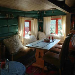 a living room with a table and chairs and windows at Restored Cabin From 1852 In Bergsjø Area in Skarsgård
