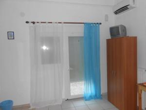 a room with a window with blue and white curtains at To Pithari in Skala Marion +114 photos