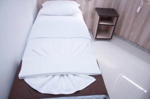 two beds in a room with a side table at Hotel Domus Itabira in Itabira