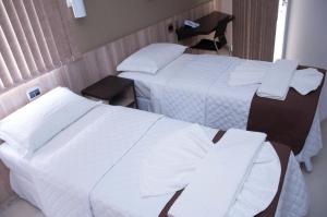 a hotel room with two beds and a chair at Hotel Domus Itabira in Itabira