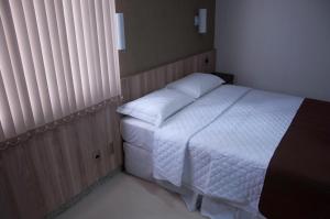 a bedroom with a bed with white sheets and pillows at Hotel Domus Itabira in Itabira